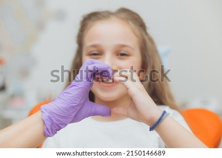 Selective focus of hands of dentist and little girl patient in heart shape