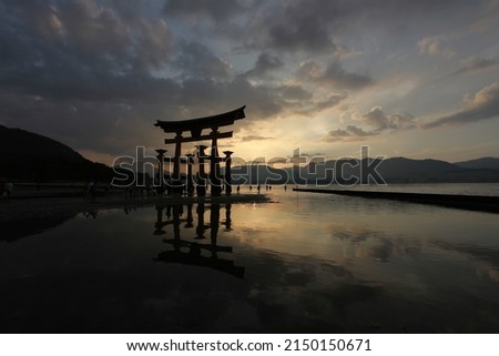 Japanese Tori at sunset. Temple entrance in the water. Beautiful cloudy evening. Religious symbol.