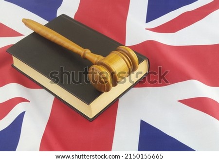Wooden judge gavel on black legal book on UK flag background. United Kingdom laws concept.	