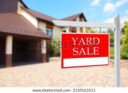Sign with text YARD SALE near modern house on sunny day