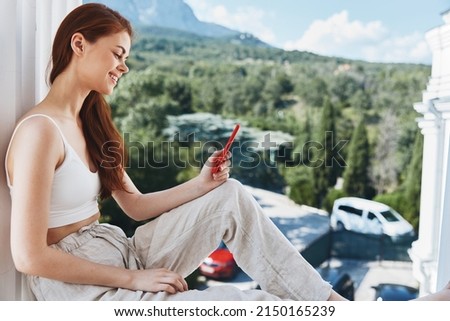 Attractive young woman sitting on the balcony with phone beautiful mountain view summer Relaxation concept