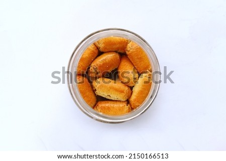 Indonesian traditional cake served in month of ramadan named "nastar" i.e. cookies with pineapple jam inside, placed on a glass jar, isolated on white background