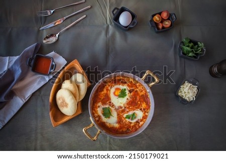 Shakshouka origonated in Tunisia is a dish of eggs poached in a sauce of tomatoes, olive oil, peppers, onion and garlic, commonly spiced with cumin, paprika and cayenne pepper served with pita bread.