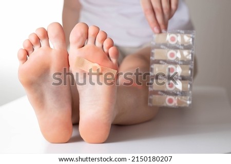 The girl holds in her hand a set of medical plasters for plantar warts. Treatment of calluses on the feet, virus Royalty-Free Stock Photo #2150180207