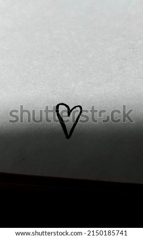 Drawing of a black heart on a white paper with shadows