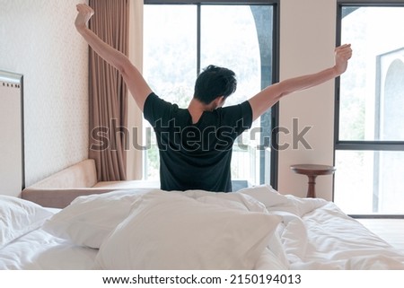 Man stretching in the morning after getting up. Man wake up and stretching in morning with sunlight by the window.  Royalty-Free Stock Photo #2150194013