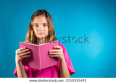 Purposeful girl in pink leafing through a book. The concept of school, education, self-study, reading books, poetry and creativity, keeping a diary, romance novels, traditional values.