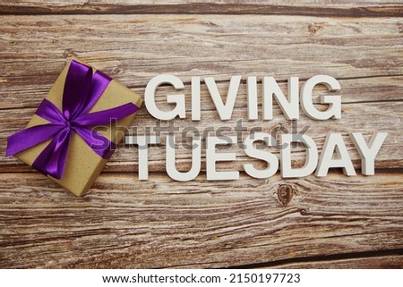 Giving Tuesday alphabet letters and gift box on wooden background