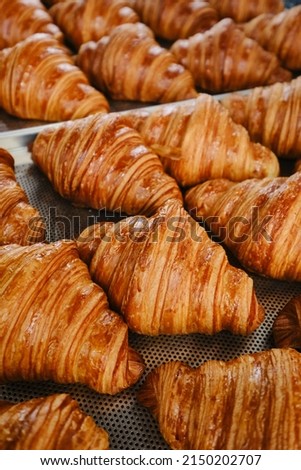 Hand takes fresh golden French croissant from the baking sheet. Fresh classic pastries Royalty-Free Stock Photo #2150202707