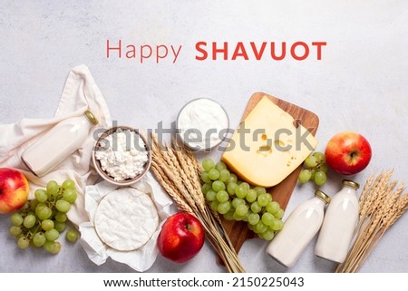 Shavuot flat lay with dairy products, first fruits and wheat on light gray background. Jewish Shavuot holiday frame with dairy foods and fruits and quote happy Shavuot, top view Royalty-Free Stock Photo #2150225043