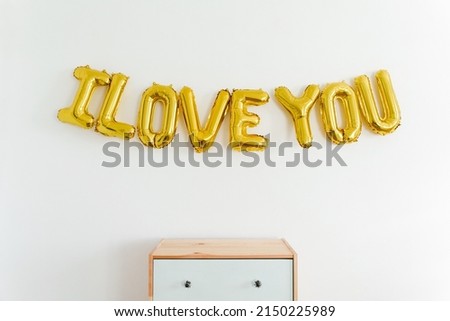 Inscription I LOVE YOU, foil inflatable gold ballon on the wall. Love, romance and Valentines day concept. Flat lay with copy space