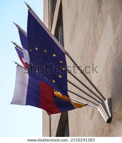 Many different flags hanging from the building. European union, France, United States of America and Russian Federation. 