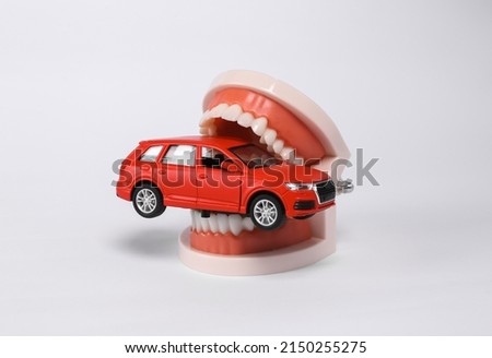 Human jaw with car model isolated on white background
