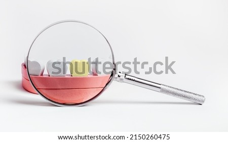 Magnifying glass over sick tooth with plaque in jaw model. Teeth checkup, caries, decay treatment concept. Oral health problems diagnosis. High quality photo Royalty-Free Stock Photo #2150260475