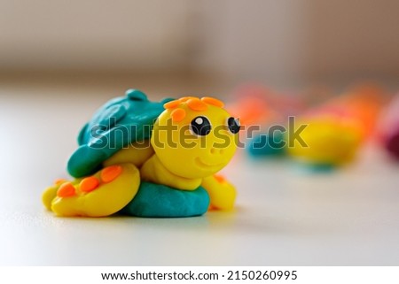 smiling plasticine turtle on white background, children's crafts made of plasticine, closeup, creativity concept