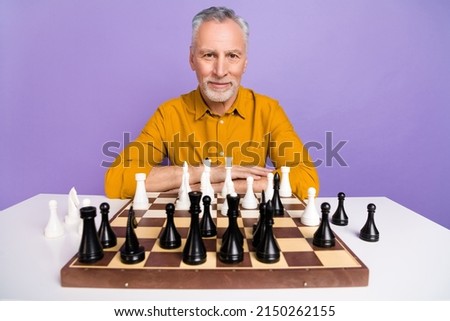 Photo of senior handsome man sit table play chess weekend competition isolated over purple color background