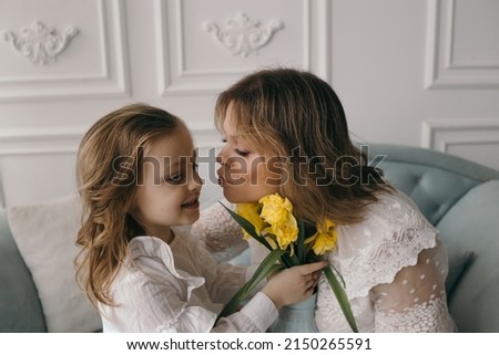 happy mother's day! child daughter congratulates mother and gives a bouquet of flowers to narcissus and gift