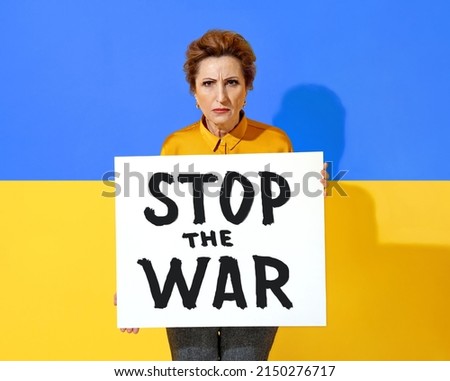 Ukrainian woman holds poster with the inscription "STOP THE WAR" against the background of the flag of Ukraine