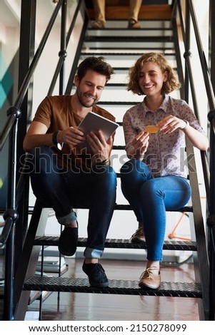 Collaboration gives the best results. Shot of two designers discussing something on a tablet while sitting on a staircase.
