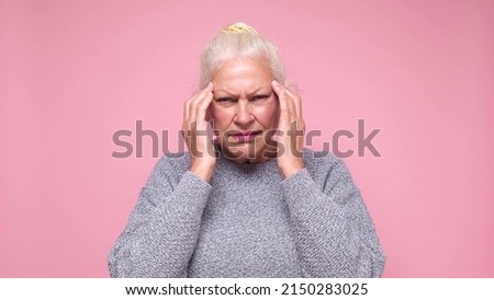 Senior woman suffering from headache desperate and stressed because of pain and migraine. She is holding hands on head.