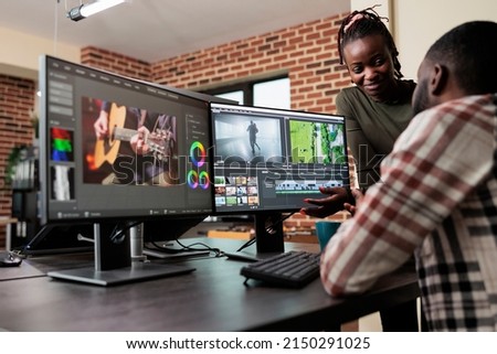 Post production department leader advising colleague to improve colors and frames quality of footage. Creative professional video editors collaborating in order to finish film project upon deadline.