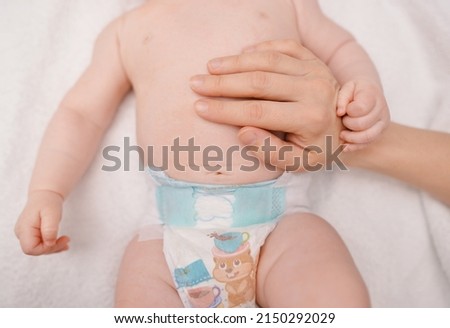 Treatment of newborn baby navel. Mother's hand and newborn's navel. First days after birth. Daily grooming. Care about baby clean and soft body skin.  Royalty-Free Stock Photo #2150292029