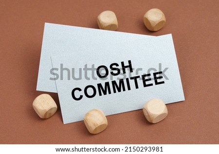 The concept of industrial safety. On a brown surface, wooden cubes and a business card with the inscription - OSH Commitee