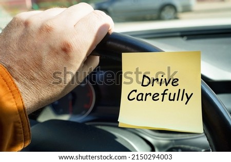 The concept of transport security. A man holds on to the steering wheel, next to a sticker with the inscription - Drive Carefully Royalty-Free Stock Photo #2150294003
