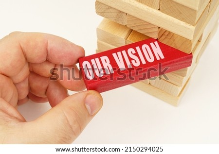 Business and technology concept. From the tower with wooden planks, they take out a red plaque with the inscription - Our vision