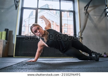 Midget woman standing in side plank, training at the gym Royalty-Free Stock Photo #2150296491