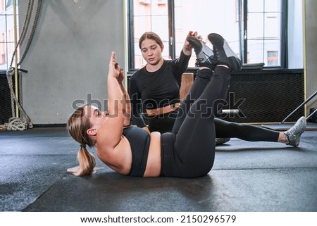 Trainer assisting to midget woman while she doing exercises at the gym Royalty-Free Stock Photo #2150296579