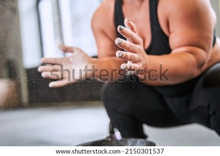 Midget female athlete clapping hands with chalk powder before strength training at the gym Royalty-Free Stock Photo #2150301537