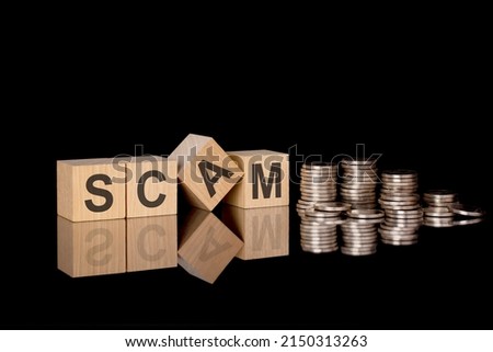 Scam. wooden cubes. black background. stacks with coins. inscription on the cubes is reflected from the surface of the table. business concept.