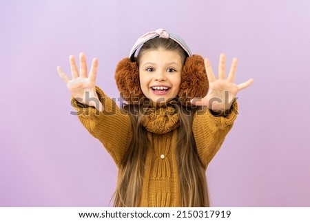 The onset of the cold season, a girl in a warm sweater and fur headphones on her head.