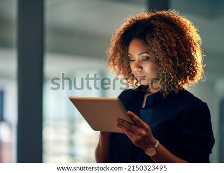 Working smart, working hard. Shot of a young businesswoman using a digital tablet during a late night at work. Royalty-Free Stock Photo #2150323495