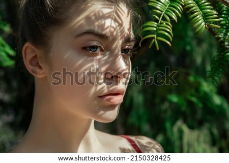 Beautiful young woman with light and shadow on her perfect skin posing on nature. Spa, skincare and wellness. Selective focus. Close-up
