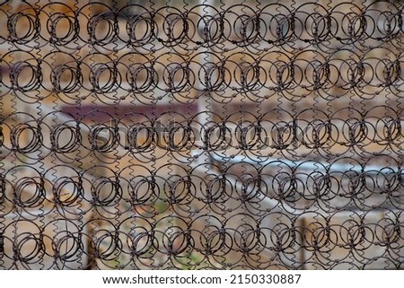 close up abstract of bed springs fence many circular geometric spiral springs in rows rusty metal bed springs used for privacy fence shapes small to large connected together close up abstract backdrop
