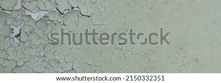 Peeling paint on the wall. Panorama of a concrete wall with old cracked flaking paint. Weathered rough painted surface with patterns of cracks and peeling. Wide panoramic grunge texture for background Royalty-Free Stock Photo #2150332351
