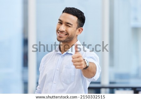 You made the right choice by picking my business. Shot of a handsome young businessman standing alone in the office and making a thumbs up gesture.