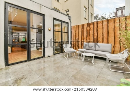 The interior of the backyard with a seating area on the marble floor and the entrance to the apartment