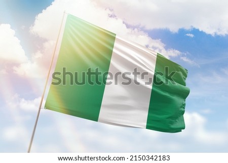 Sunny blue sky and a flagpole with the flag of nigeria