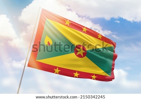 Sunny blue sky and a flagpole with the flag of grenada