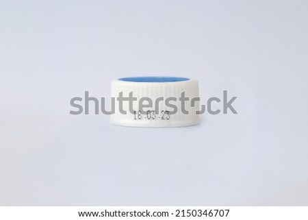 Close up image of white with top blue color bottle cap with printed dd mm yy expiry date, isolated on white background
