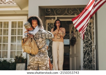 Army soldier embracing his daughter after coming back home. American serviceman surprising his wife and daughter with his return. Military man reuniting with his family after deployment. Royalty-Free Stock Photo #2150353743