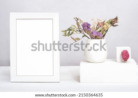 white frame with copy space and dry flowers ina vase on geometric podium or pedestal. template for text or inscription. mock up for sale advertisment or inspirational card.