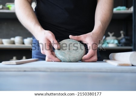 pottery, clay, ceramics art concept - closeup on hands of young master with the large pieces of fireclay. Horizontal photo