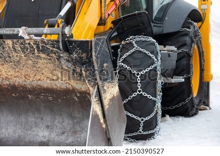 Picture of a vehicle tyre with snow chains on a frozen road   