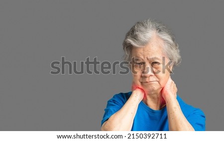 Cervical dystonia disease. Senior woman suffering neck pain while standing against a gray background. Side view. Neuralgia of the occipital nerve. Medical and healthcare concept