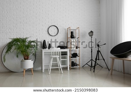 Interior of modern photo studio with comfortable workplace and different equipment