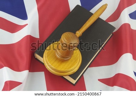 Wooden gavel on book on British flag background, top view.